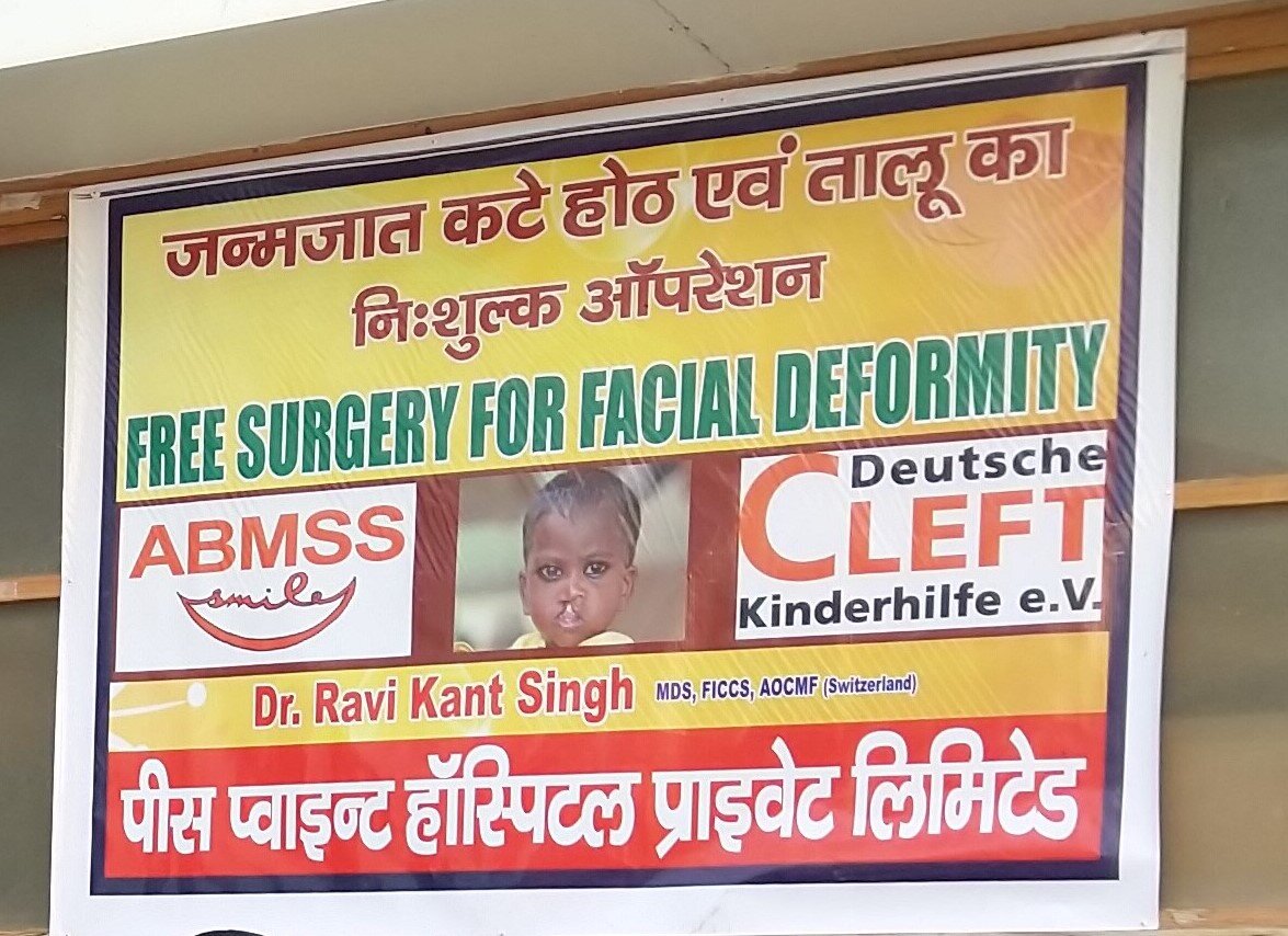 Unser Logo und das unserer indischen Partnerorganisation ABMSS auf einem Plakat für unser Hilfsangebot für Kinder mit Lippen-Kiefer-Gaumenspalten in Varanasi, Indien.